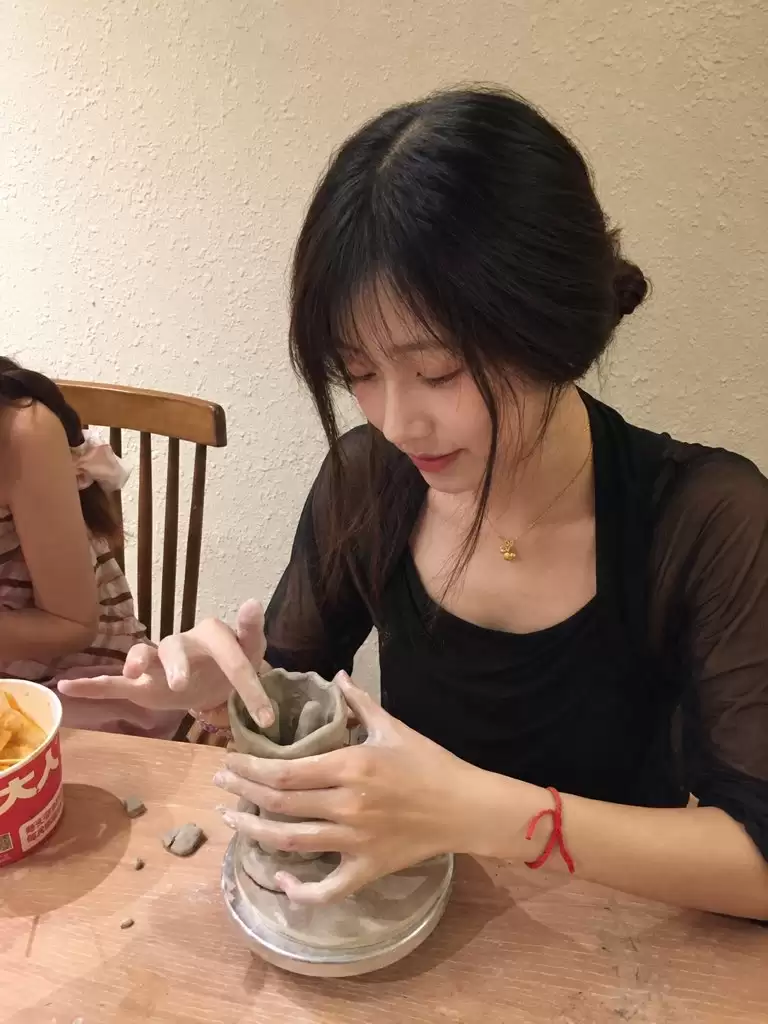 提示词：以上传人物照片作为唯一身份与面部参考，生成一组真实自然的陶艺体验生活照。成年女性，长黑发